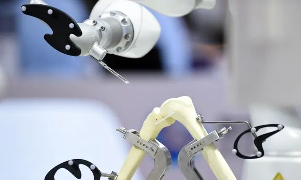 A robotic arm performs surgery on a joint model during the 2022 World Robot Conference in Beijing